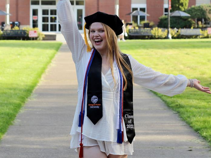 Breanna Repp with her cap and tassels in front of the Valley Library.