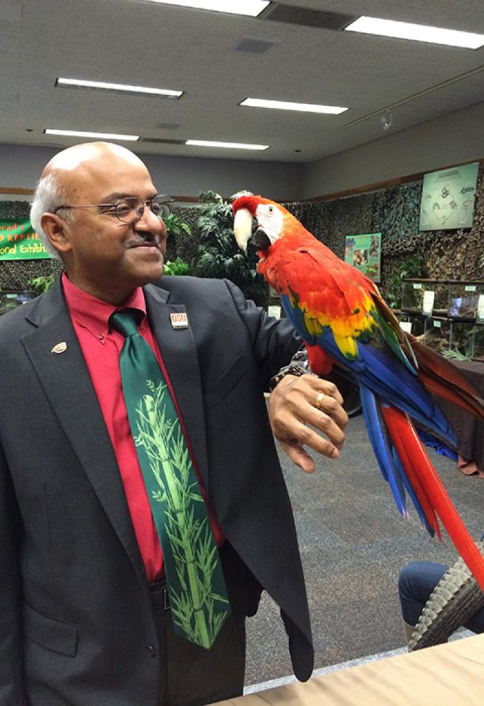 Sastry Pantula holding a scarlet macaw