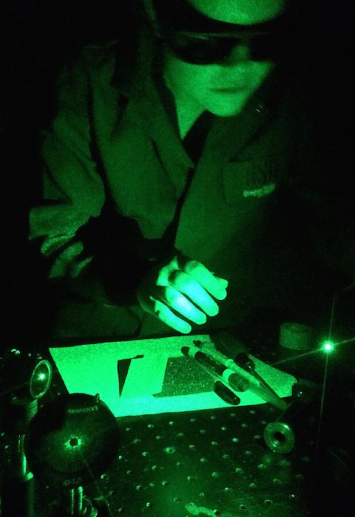 green light filter over Shan Lansing working with lab equipment