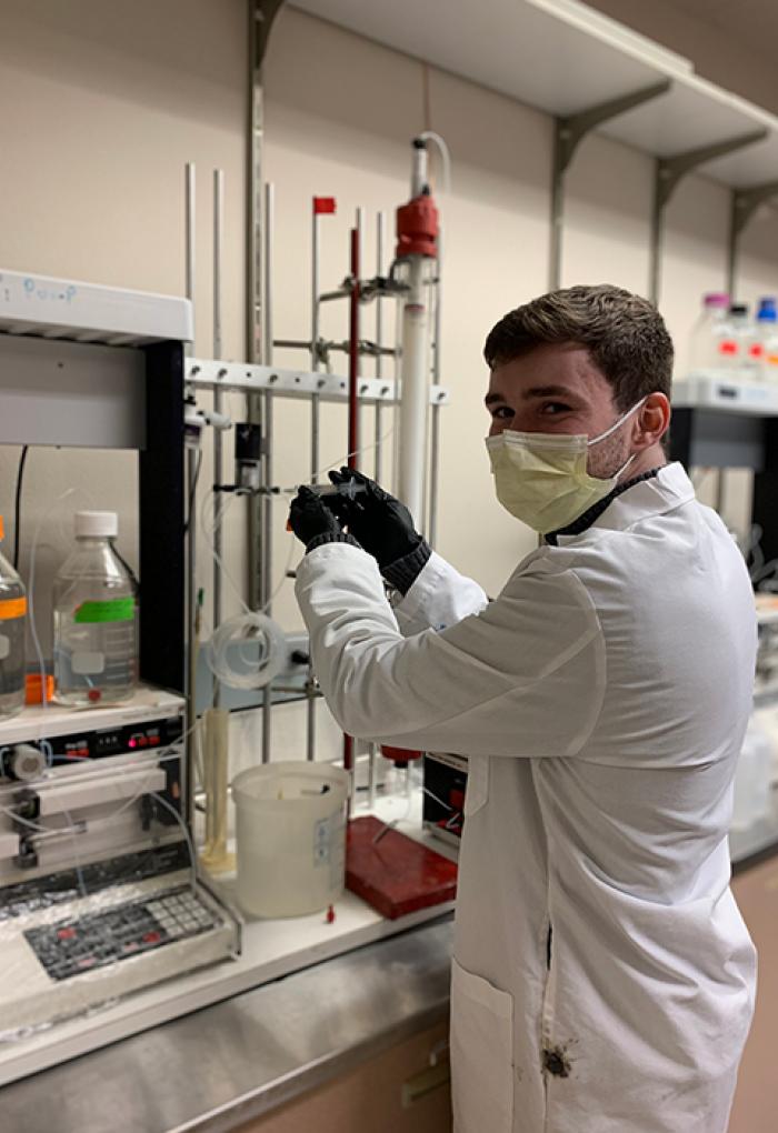 Seth Pinckney in a lab coat and face mask in a scientific laboratory