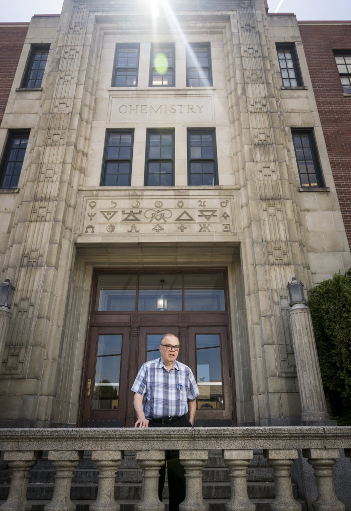 A man standing in front of the brick building.