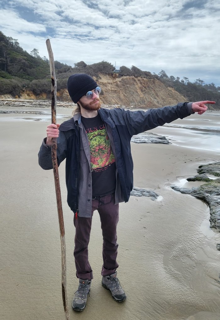 A man holds a stick on the beach.