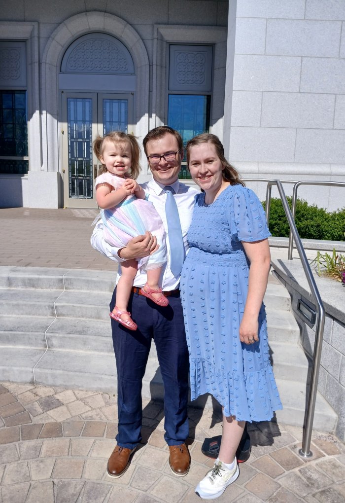 A man and woman pose for a photo with a young child.