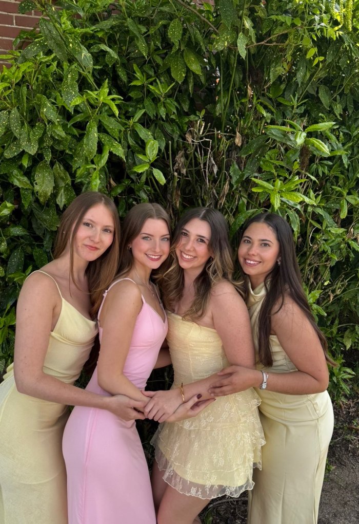 A group of women pose for a photo in dresses.