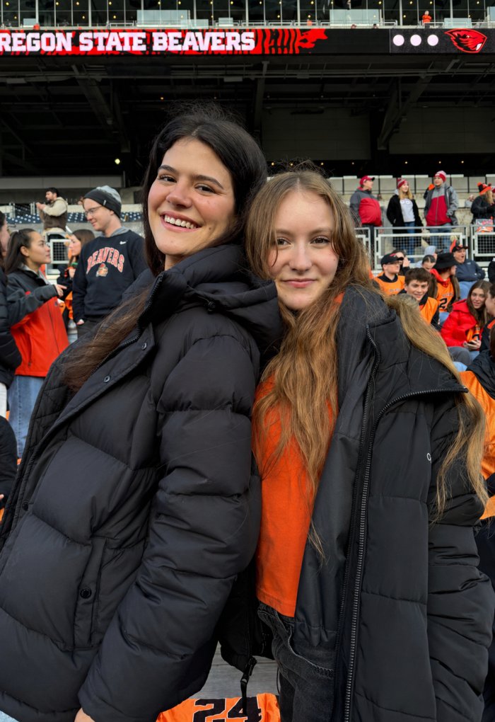 Two women pose for a photo at a football game.