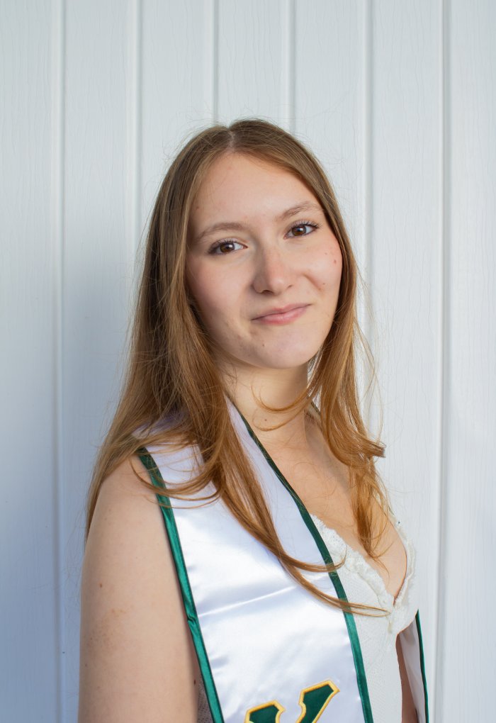 A woman poses for a photo in her graduation dress and stole.