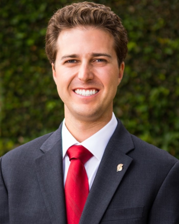 Smiling headshot of Chris in a suit and tie