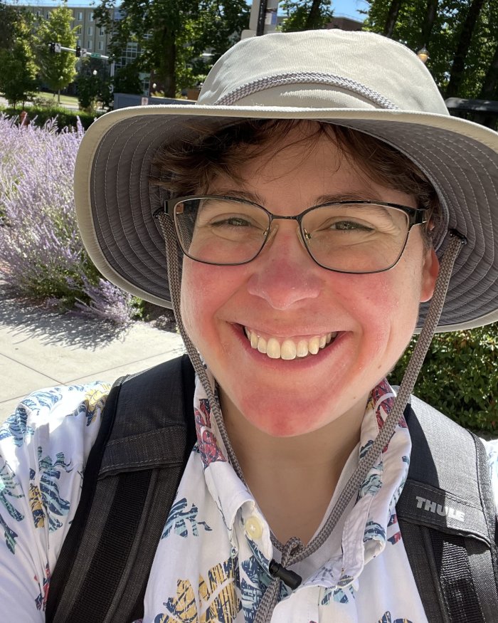 Ashely Stengel outside on a sunny day, wearing a hat and a backpack.