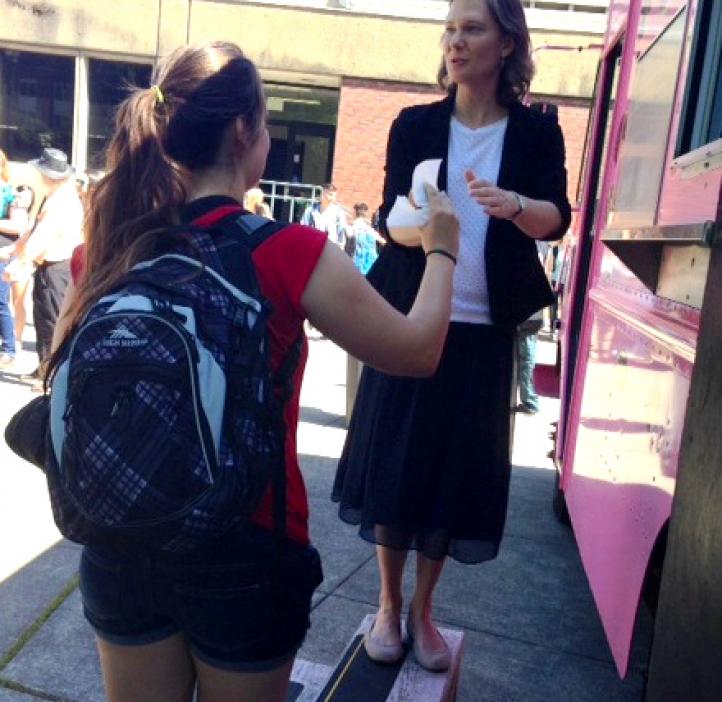 student grabbing donut from pink delivery truck