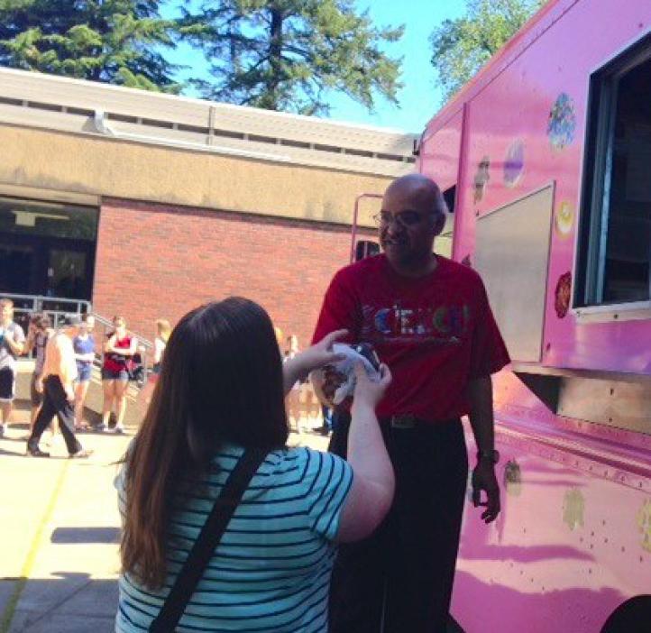 student grabbing donut from pink delivery truck