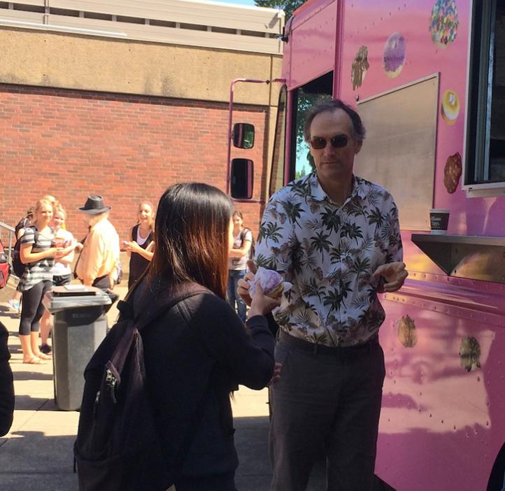 Student grabbing donut from pink delivery truck