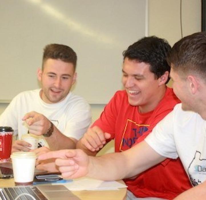 male students laughing while working on homework
