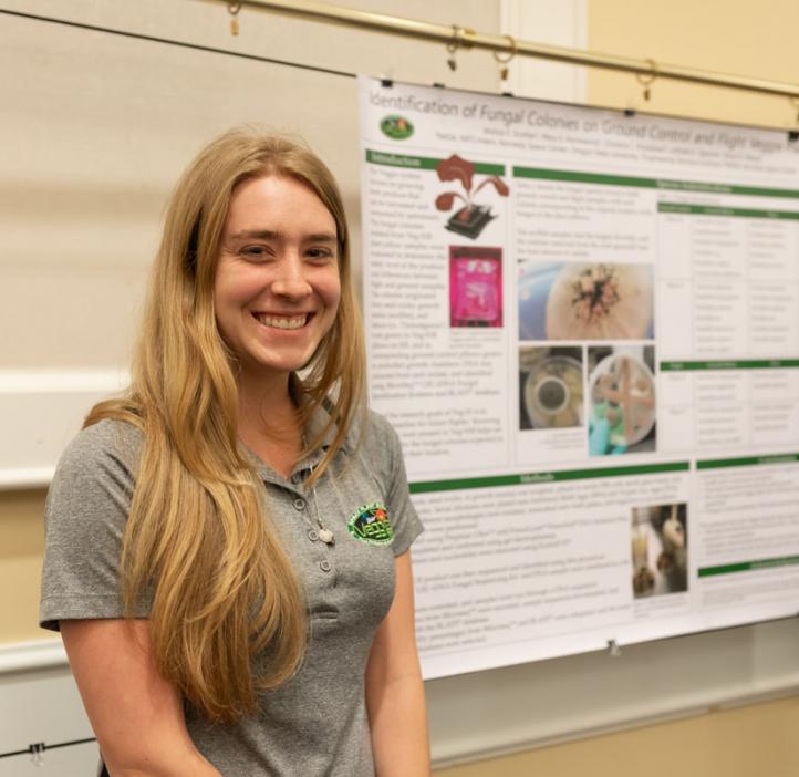Jessica Scotten smiling next to her research poster