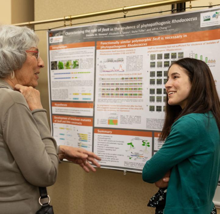 female student explaining her research poster with colleague