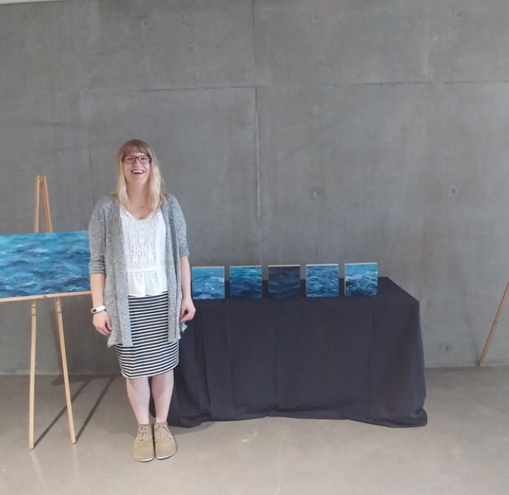 Abigail Losli standing with her paintings