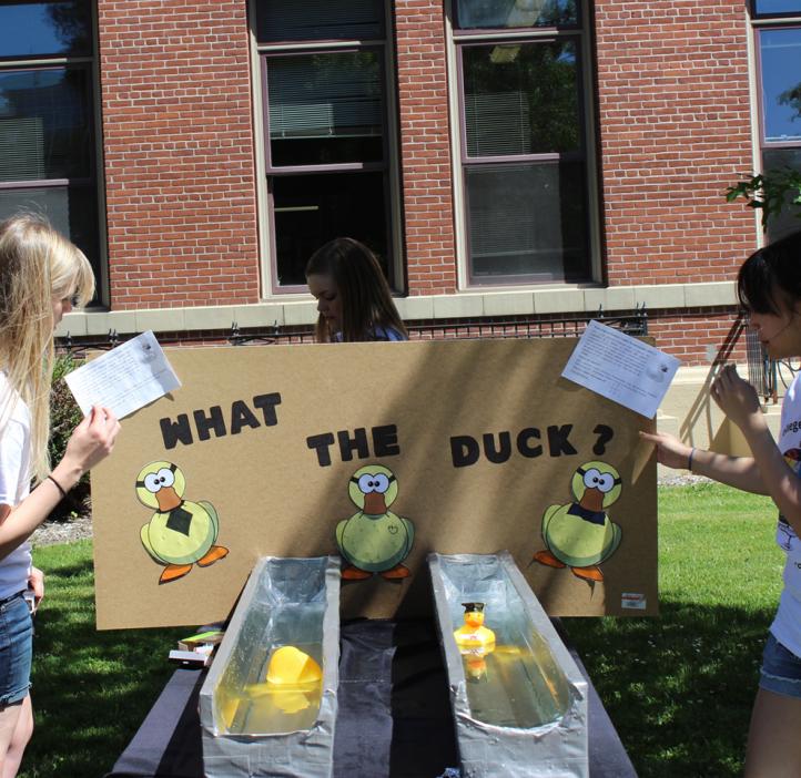 female students presenting club booth of swimming duck exhibit