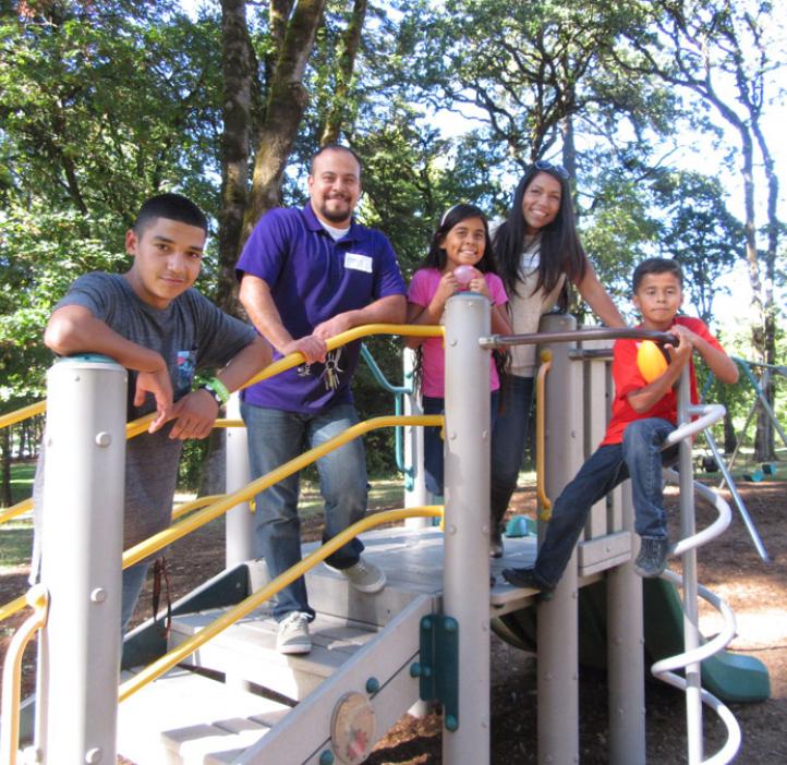 family standing on play structure
