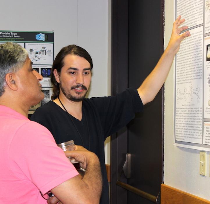 male student presenting poster to colleague