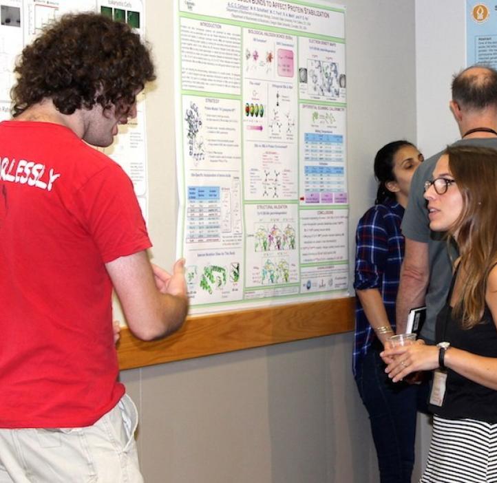 male student presenting poster to female attendee