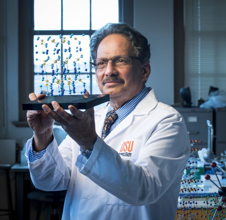 Mas Subramanian stands in a lab holding a structure of YInMn Blue.