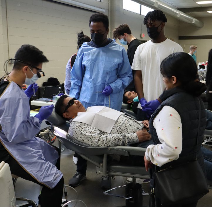 Students help a community member receive dental care.