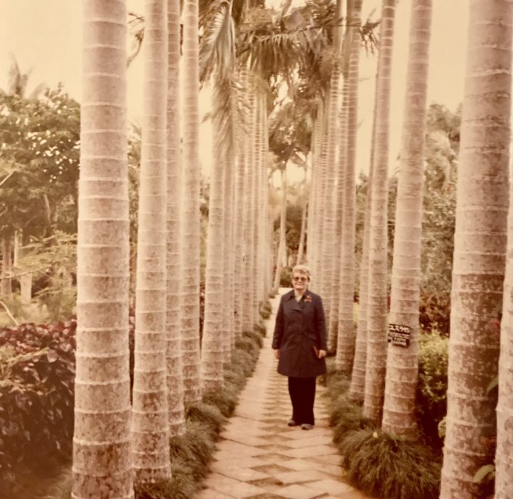 Eleanor Ford stands on a stone pathway with palm trees in Okinawa, Japan in 1981.