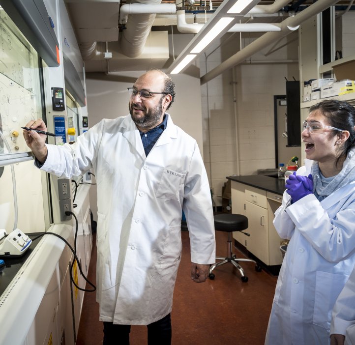 A man in a lab coat works with two students.
