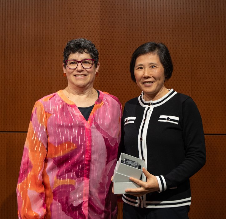 A woman in a pink blouse stands next to a black blouse.