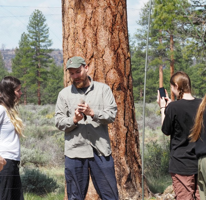 Students gather around a researcher holding a bird.