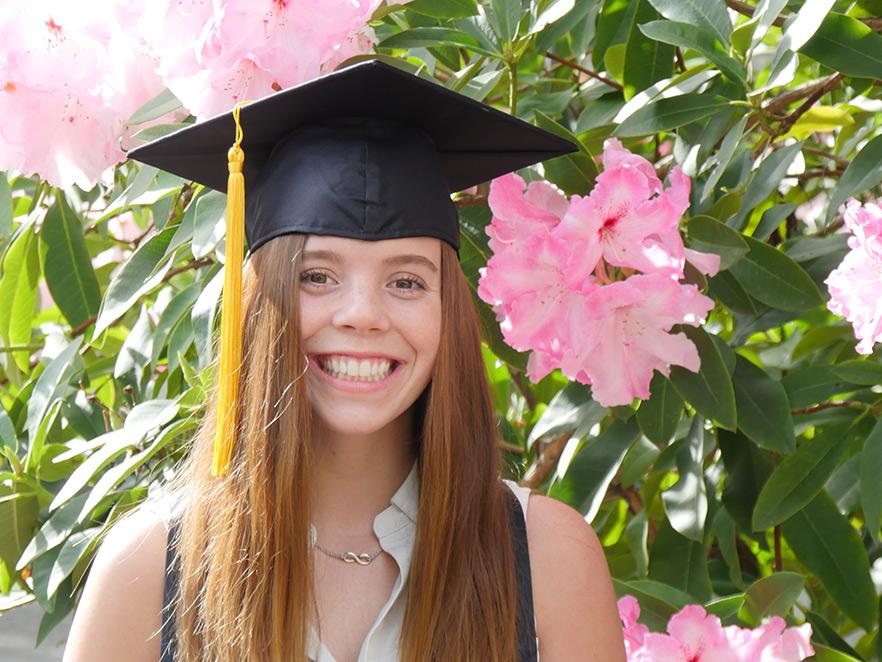 Sarah Bright wearing graduation cap in front of rose bush