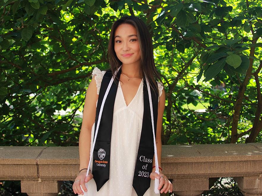 Thanh Nguyen standing outdoors wearing her commencement tassels.